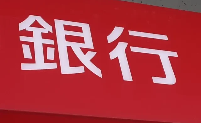 Image of a person using a bank ATM, highlighting important Japanese financial terms.