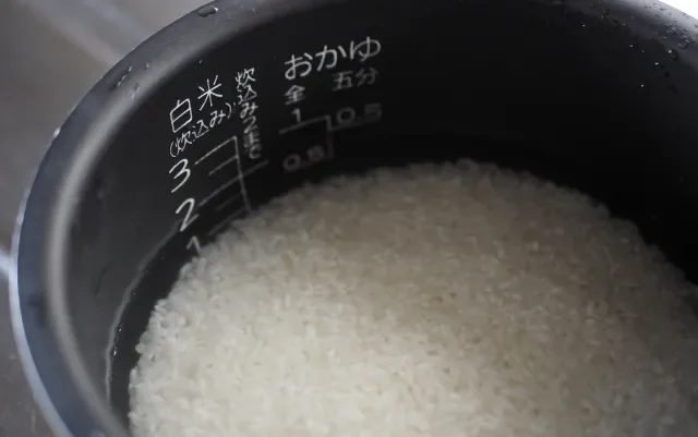 Image illustrating the correct water to rice ratio and the water level mark on a rice cooker pot.