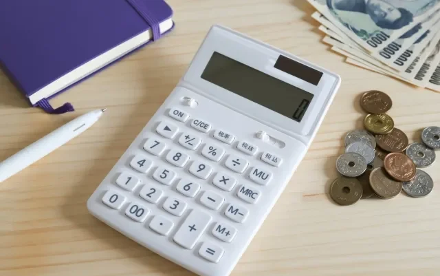 Image illustrating a person budget planning with receipts and a calculator, focusing on saving money.