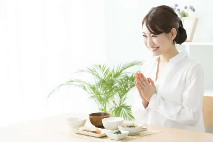Image illustrating the correct posture and hand gesture for saying 'Itadakimasu' before a meal.