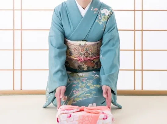 Image of a woman wearing a Hōmongi kimono, which has continuous patterns over the seams and shoulders.