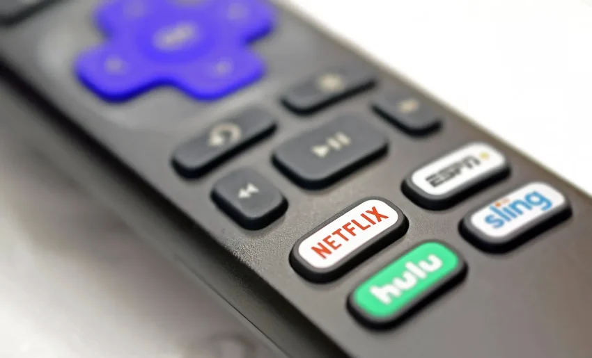Image of a person holding a remote control while watching missed TV programs on a large screen.